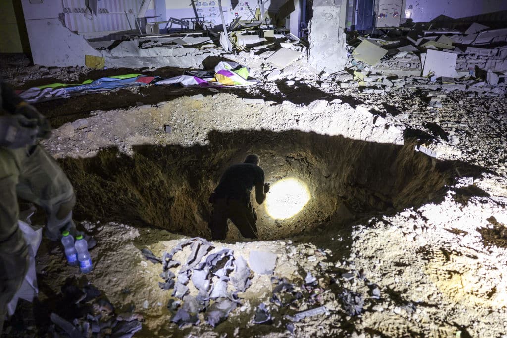 TOPSHOT - Members of Israel's Home Front Command and police forces inspect a crater left by an exploded projectile at a heavily-damaged school building in Israel's southern city of Gedera on October 1, 2024, after Iran launched a barrage of missiles at Israel in response to the killings of Lebanese Hezbollah leader Nasrallah and other Iran-backed militants. Reports said Iran fired between 150 and 200 missiles in the attack, the country's second on Israel after a missile and drone attack in April in response to a deadly Israeli air strike on the Iranian consulate in Damascus. (Photo by Menahem KAHANA / AFP) (Photo by MENAHEM KAHANA/AFP via Getty Images)