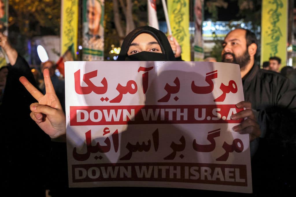 A woman holds a sign denouncing the US and Israel during a rally celebrating after Iran launched a barrage of missiles at Israel in response to the killings of Hezbollah's leader Hassan Nasrallah and other Iran-backed militants outside Imam Jaafar Sadiq Mosque in Tehran's Palestine Square on October 1, 2024.