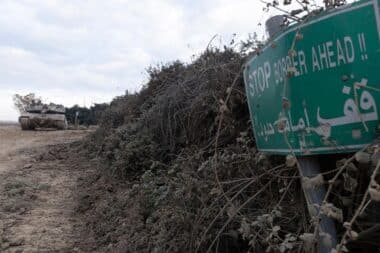 An Israeli tank is parked near a sign warning of the border with Lebanon on December 4, 2024 in Metula, Israel.