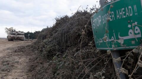 An Israeli tank is parked near a sign warning of the border with Lebanon on December 4, 2024 in Metula, Israel.